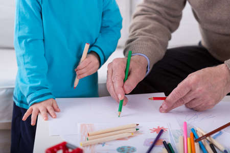 Close-up of grandfather and grandson drawing picture together