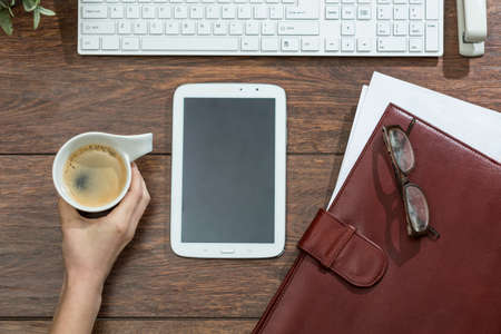 Woman's hand reaching for cup of black coffee from deskの写真素材