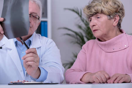 Professional physician analyzing the xray photo of his female patientの写真素材