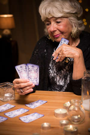 Image of smiling elder female tarot reader holding cards