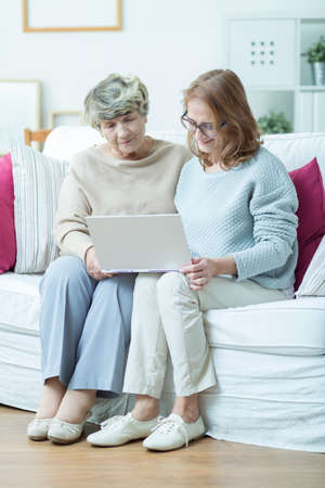 Portrait of elderly woman learning computer skills with friendの写真素材