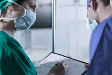 Surgeons with protective mask discussing before operationの写真素材