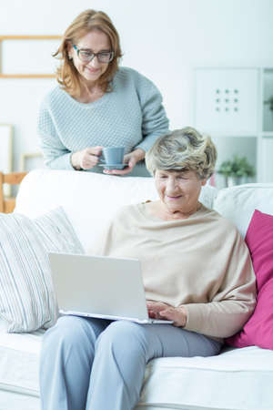 Image of senior female sitting on sofa with laptop