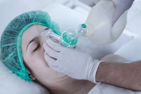Unconscious young woman lying in oxygen maskの写真素材