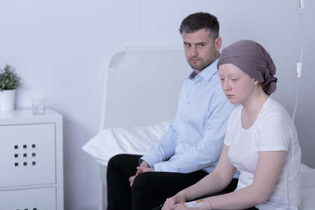 Worried girl with cancer and her helpful loving dadの写真素材