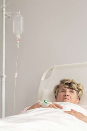 Aged lady with serious disease lying under the drip