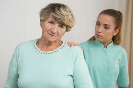 Photo of worried old female having support of nice nurseの写真素材
