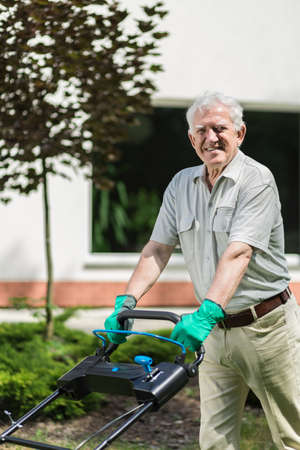 Image of elder gardener with lawn mowerの写真素材