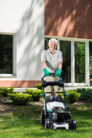 Elder man mowing grass in the gardenの写真素材
