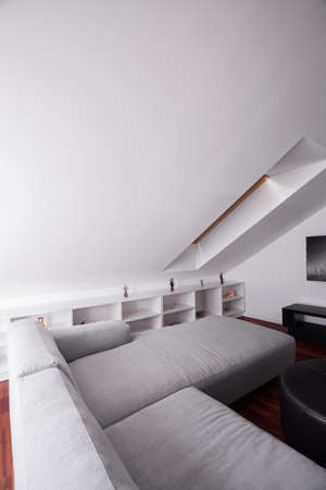 Comfortable sofa in attic room in modern residence