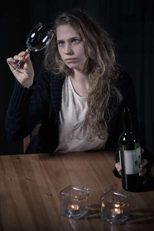 Young alcoholic woman looking at clean glassの写真素材
