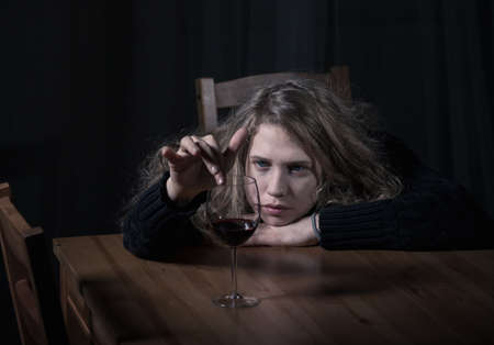 Young woman with glass of wine thinking about lifeの写真素材