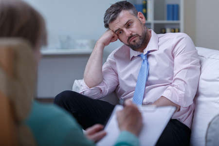 Picture of despair young businessman during psychotherapy sessionの写真素材
