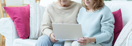 Carer is showing elder lady how to use computerの写真素材