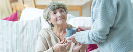 Carer give drink to lady under her charge