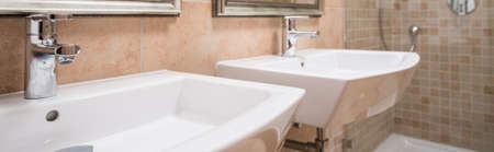 Ceramic washbasins in caramel tiled modern bathroomの写真素材
