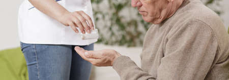Female nurse applying medicament for senior manの写真素材