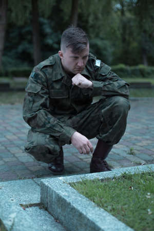 Image of young caucasian soldier visiting cemeteryの写真素材