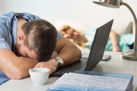 Tired overworked doctor sleeping on the deskの写真素材