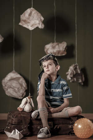 Little dreamer sitting on old leather suitcaseの写真素材