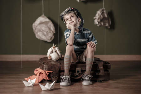 Little daydreamer sitting on suitcase and dreaming about divingの写真素材