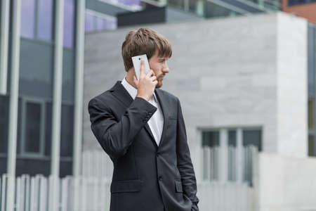 Young man in suit is standing outside of companyの写真素材