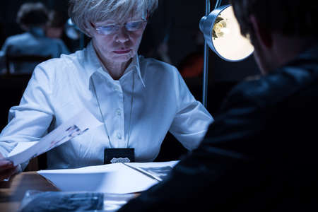 Image of elder policewoman examining a suspected man