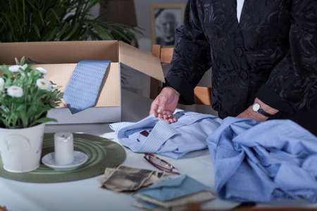 Woman in mourning packing souvenirs after dead husbandの写真素材