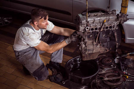 Photo of handsome service station worker repairing motor car