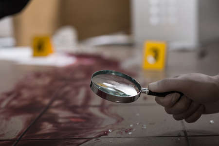 Forensic scientist looking blood through magnifying glassの写真素材
