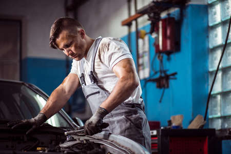 Image of professional uniformed car mechanic working in service stationの写真素材