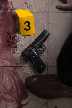 Close-up of blood and gun - evidence of murder