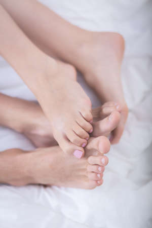 Close up of feet of romantic couple lying in bedの写真素材