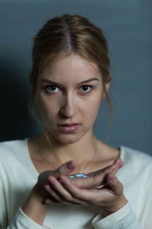 Photo of depressed female holding handful of sleeping pillsの写真素材