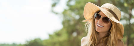 Panoramic picture of smiling girl in panama hat and sunglassesの写真素材