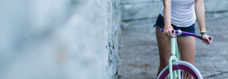Panoramic view of girl with bike standing by the wallの写真素材