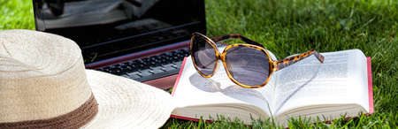 Hat, book, sunglasses and notebook on a grassの写真素材