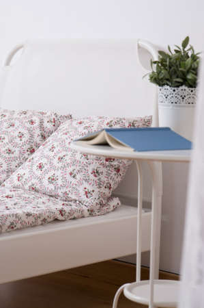 Image of simple white nighstand standing beside single bedの写真素材