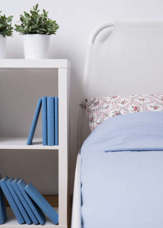 Image of small white wooden bookcase beside bedの写真素材