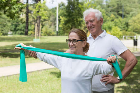 Image of senior female exercising with pilates band outside