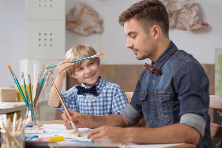 Image of talented happy schoolboy with his paint teacherの写真素材