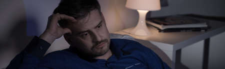 Photo of sad man sitting at night after job lossの写真素材