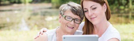 Grandmother and granddaughter looking at tablet's screen