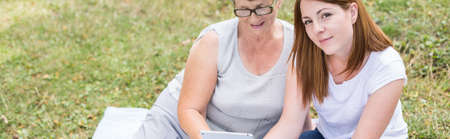 Grandmother and granddaughter sitting on the grass