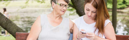 Grandmother with young granddaughter sitting in the parkの写真素材