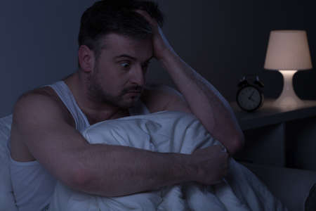 Horizontal photo of a man too stressed to fall asleepの写真素材