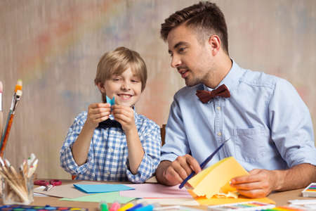 Photo of creative kid learning origami with elder brotherの写真素材