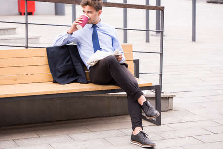 Image of elegant commuter drinking coffee while waiting for busの写真素材