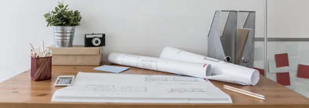 Office supplies and blueprints on wooden deskの写真素材