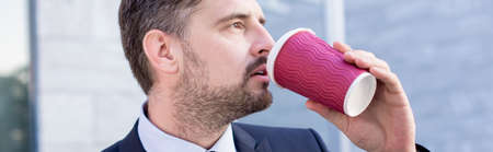 Attractive mature businessman drinking coffee at workの写真素材